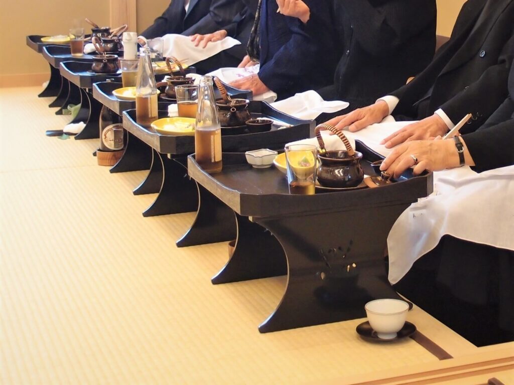 和室で食事をする喪服姿の参列者と料理