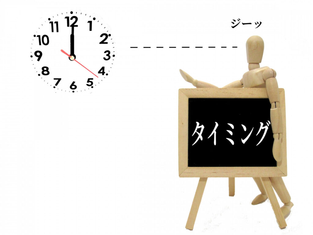 「タイミング」の文字が入った看板を脇にかかえて時計を見つめる木の人形